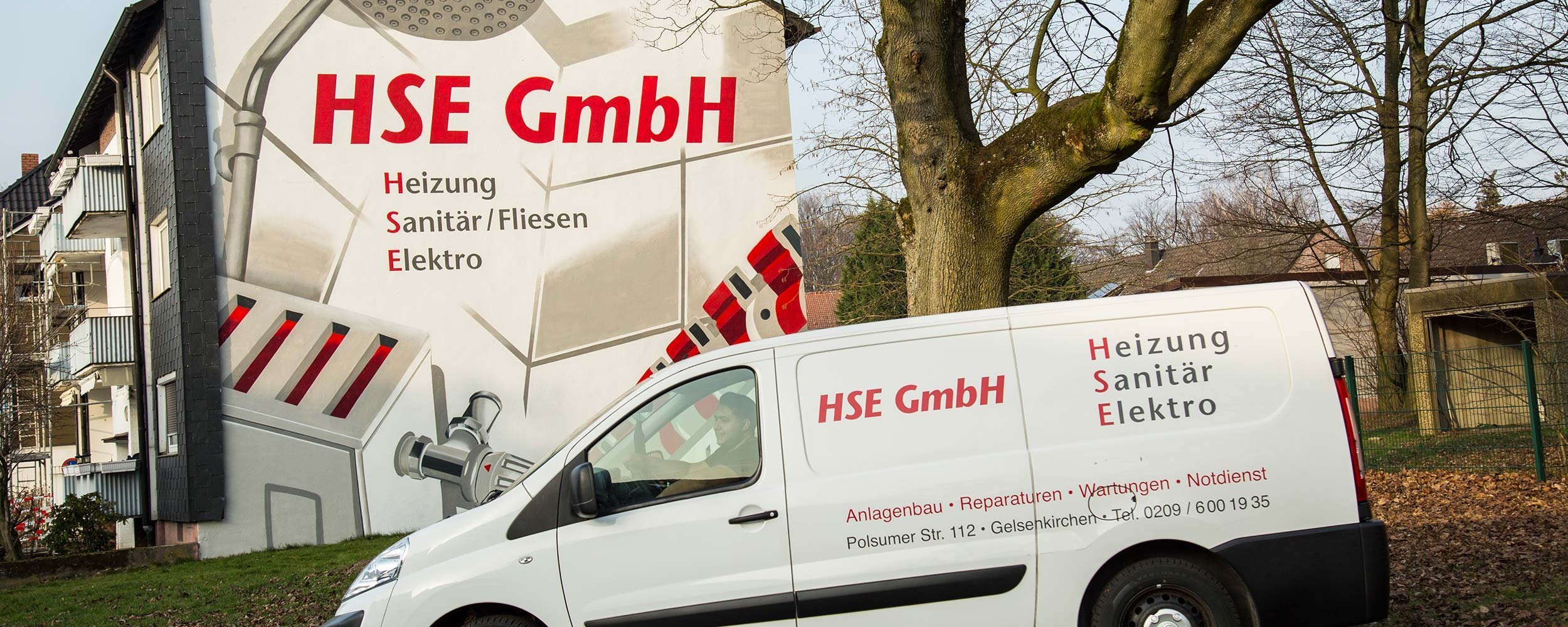 Ein Lieferwagen der HSE GmbH steht vor einer großen Wandmalerei, die Heizungs- und Sanitärdienstleistungen bewirbt.